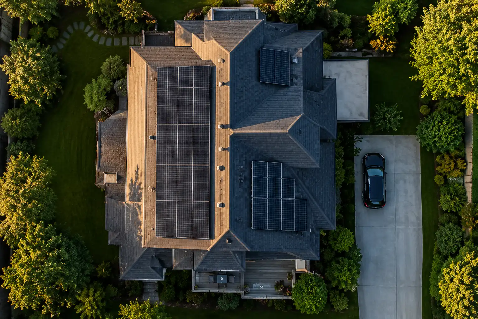 Aerial view of a home showing rooftop solar panels, driveway, electrical equipment, and battery placement